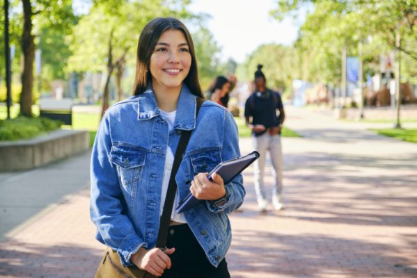 A young woman college student, standing on campus.