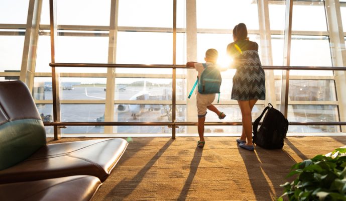 Mother and son looking through window in airport terminal.